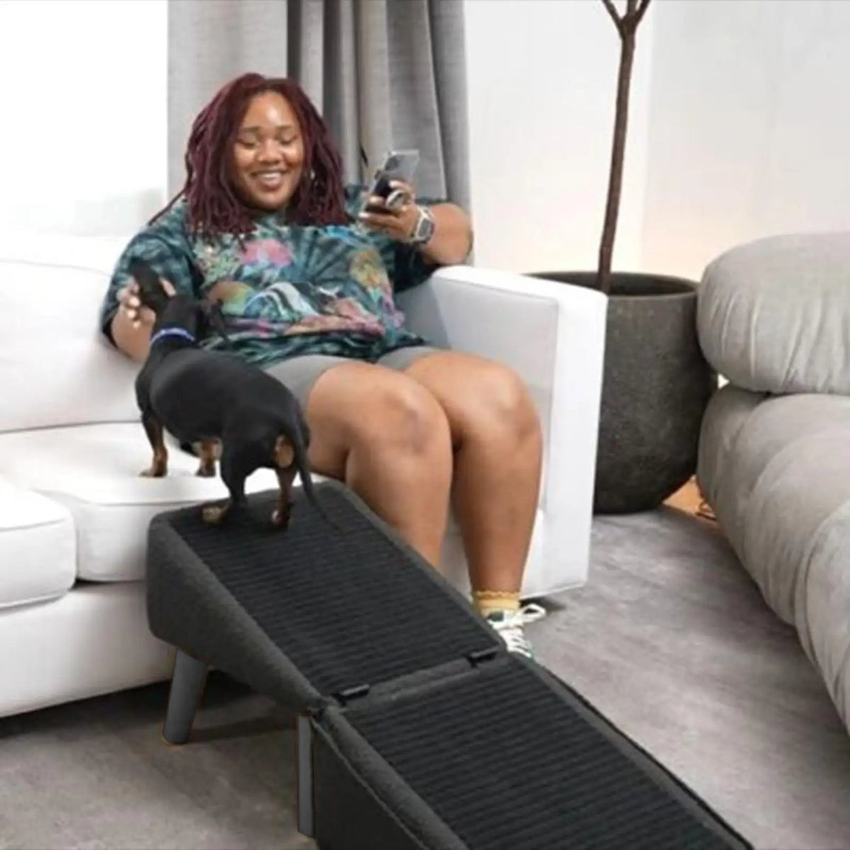 Foldable wooden pet ramp with non-slip fabric cover beside a bed